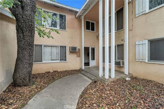 entrance to property featuring a patio area, stucco siding, and cooling unit