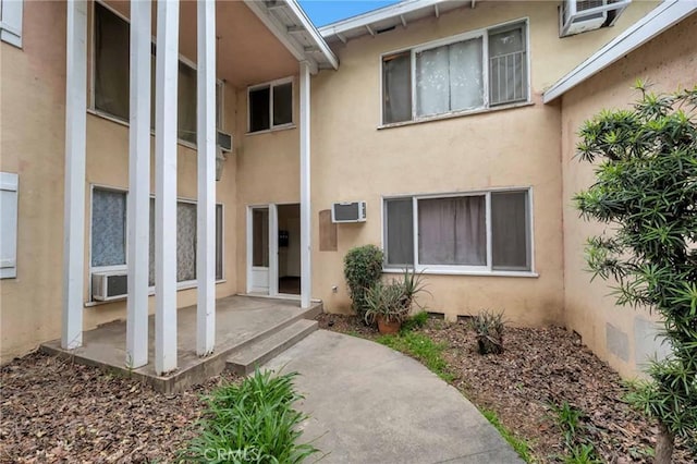 doorway to property featuring an AC wall unit and stucco siding