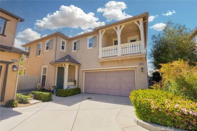 mediterranean / spanish-style house with concrete driveway, an attached garage, a balcony, and stucco siding
