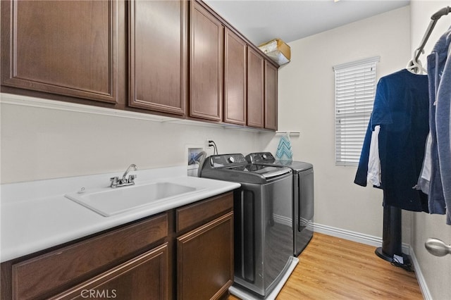 46239 Timbermine Ln, Temecula, CA 92592 - laundry area featuring washing machine and dryer, baseboards, light wood-style floors, a sink, and cabinet space