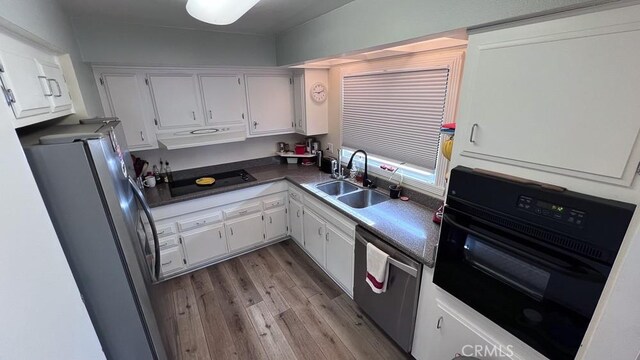 3621 Vista Campana S Unit 56, Oceanside, CA 92057 - kitchen with a sink, black appliances, under cabinet range hood, wood finished floors, and dark countertops