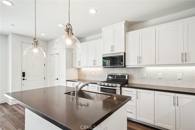 3860 S Oasis Paseo Unit 7, Ontario, CA 91761 - kitchen with stainless steel appliances, dark countertops, a sink, and dark wood-type flooring