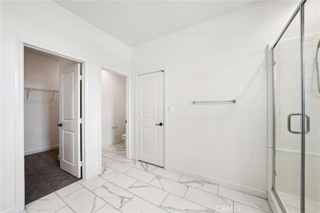 3860 S Oasis Paseo Unit 7, Ontario, CA 91761 - bathroom featuring toilet, marble finish floor, baseboards, a shower stall, and a spacious closet