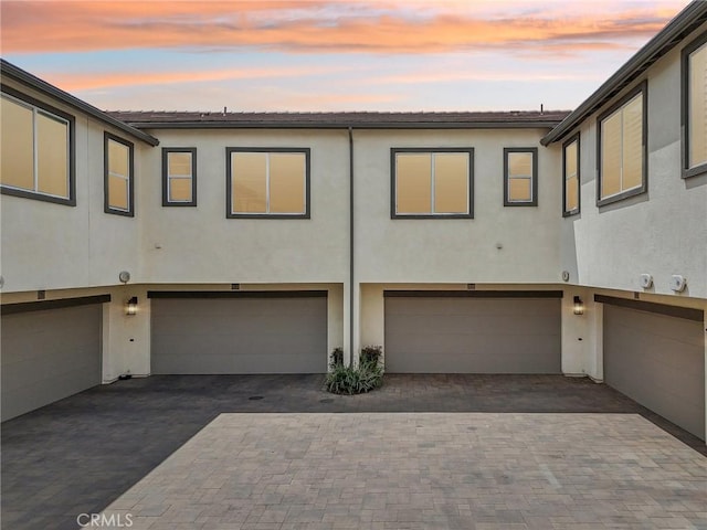 3860 S Oasis Paseo Unit 7, Ontario, CA 91761 - rear view of house with an attached garage, driveway, and stucco siding