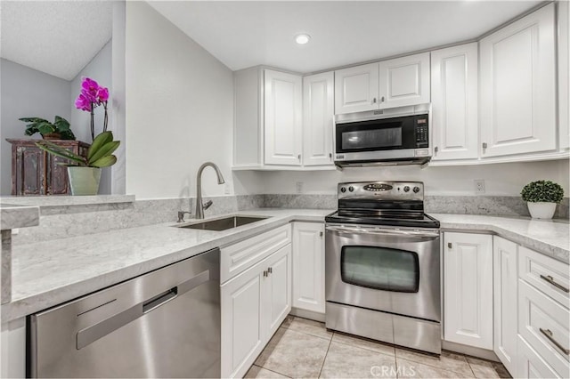 kitchen featuring recessed lighting, white cabinetry, a sink, appliances with stainless steel finishes, and light tile patterned floors