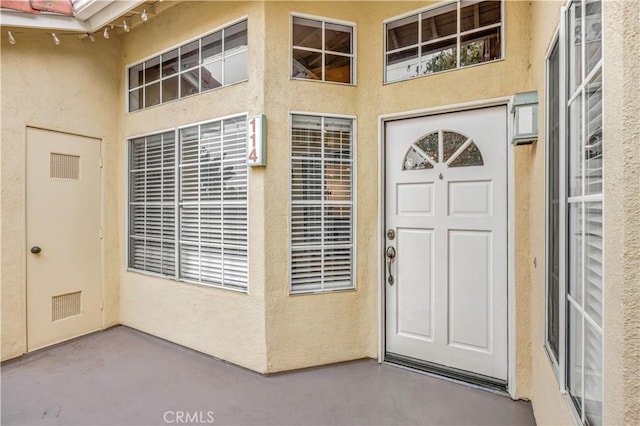entrance to property with visible vents, stucco siding, and a patio area