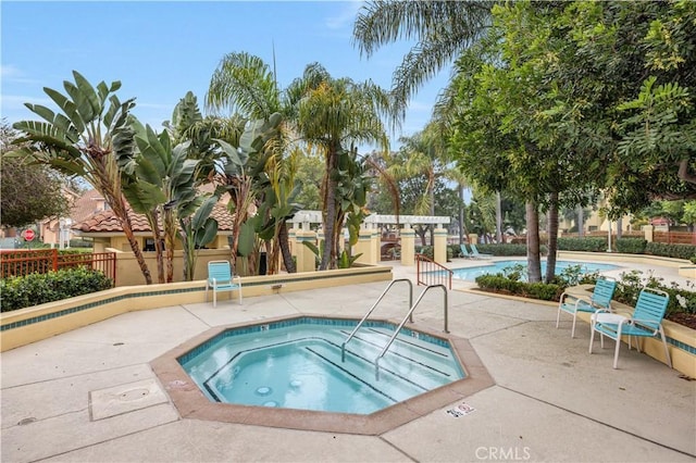 pool with fence, a community hot tub, and a patio area