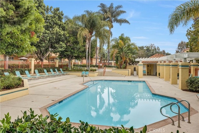 community pool with a patio and fence