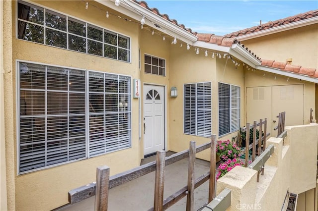 view of exterior entry featuring a tiled roof and stucco siding