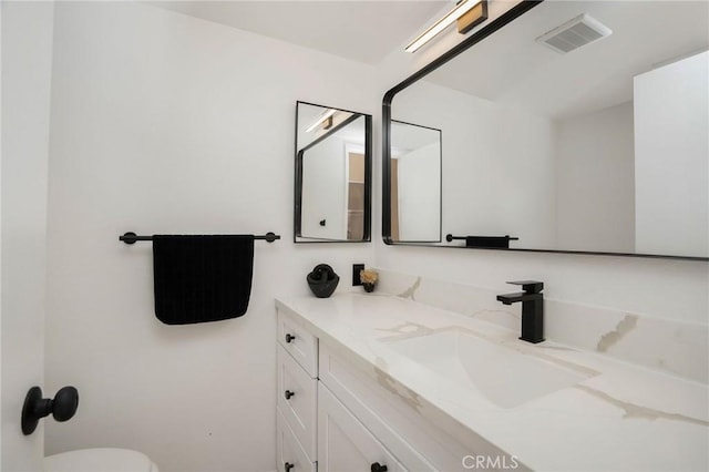 bathroom featuring visible vents, toilet, and vanity