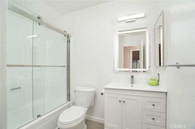 bathroom with vanity, baseboards, combined bath / shower with glass door, and toilet