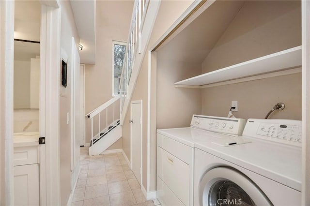 clothes washing area with baseboards, laundry area, washing machine and dryer, and light tile patterned floors