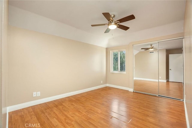 unfurnished bedroom with light wood-type flooring, a ceiling fan, baseboards, and a closet