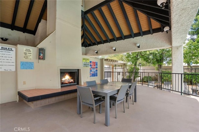 view of patio featuring a tiled fireplace, fence, outdoor dining space, and a gazebo