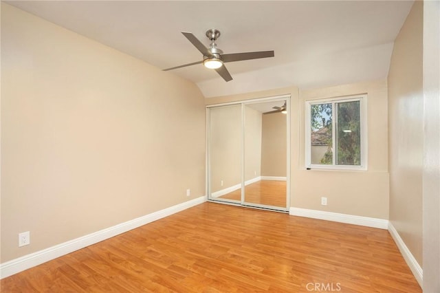 unfurnished bedroom with vaulted ceiling, baseboards, a closet, and light wood finished floors