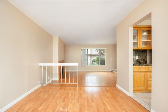 empty room with baseboards and light wood-type flooring