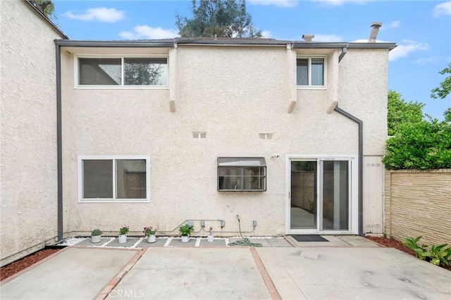 rear view of property with a patio area, stucco siding, and fence
