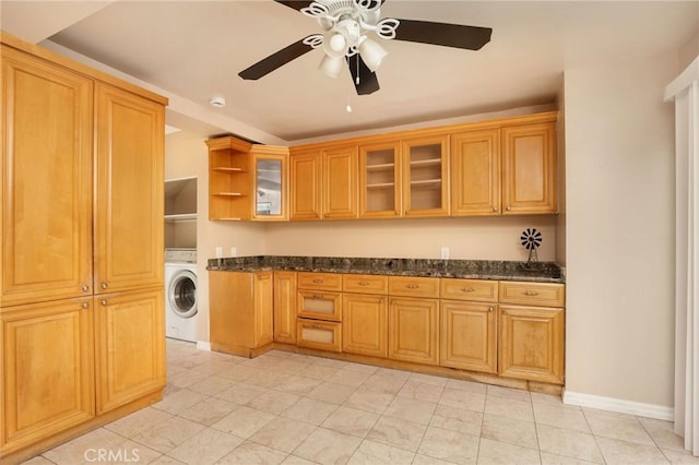 kitchen featuring open shelves, washer / dryer, ceiling fan, and dark stone counters