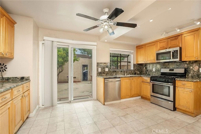 kitchen with a sink, appliances with stainless steel finishes, decorative backsplash, and a wealth of natural light
