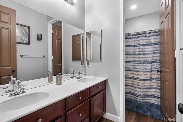 bathroom featuring double vanity, curtained shower, a sink, and wood finished floors
