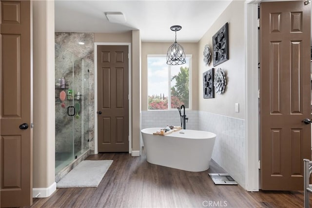 full bath with a wainscoted wall, a soaking tub, a shower stall, and wood finished floors