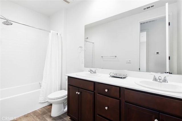 full bath featuring visible vents, a sink, shower / bath combo, and wood finished floors