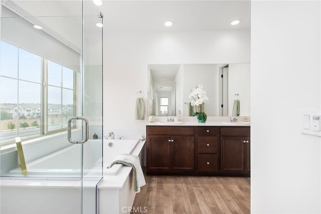 full bath featuring double vanity, a sink, a garden tub, and wood finished floors
