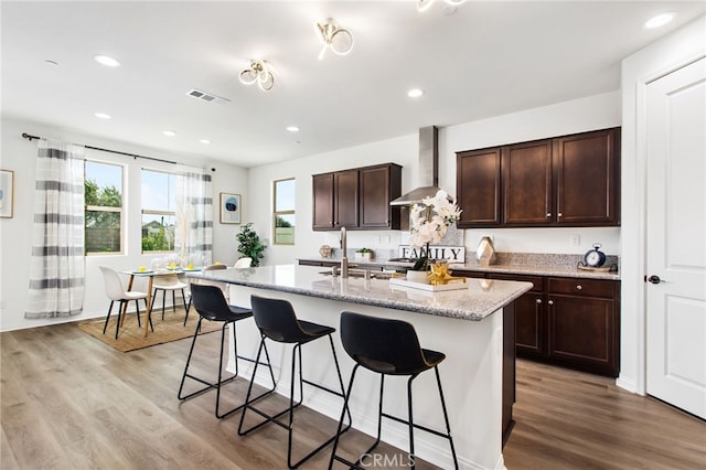 32189 Dymondia Way, Temecula, CA 92591 - kitchen featuring wall chimney exhaust hood, a sink, a breakfast bar area, light wood-style floors, and recessed lighting