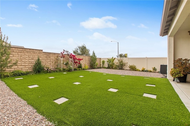 view of yard featuring a fenced backyard and central AC