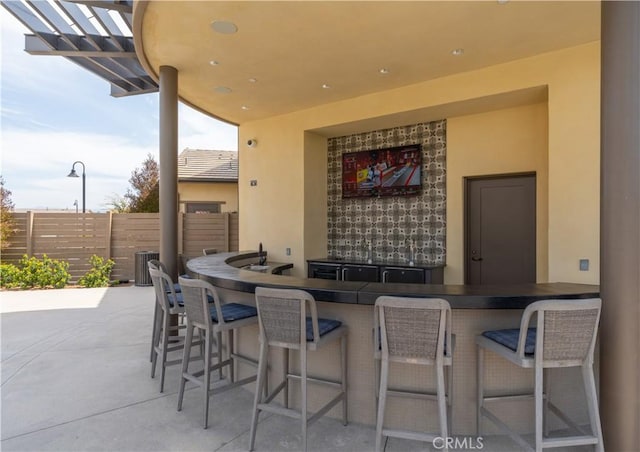 view of patio featuring central air condition unit, outdoor wet bar, and fence