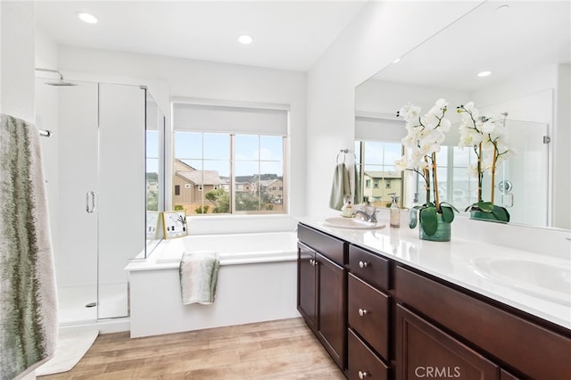 bathroom with a garden tub, a sink, wood finished floors, and a shower stall