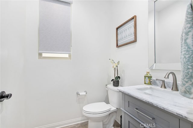 bathroom with toilet, baseboards, and vanity