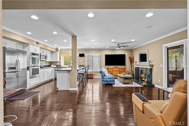 24239 Bella Ct, Newhall, CA 91321 - living area with crown molding, recessed lighting, a ceiling fan, dark wood-type flooring, and a high end fireplace