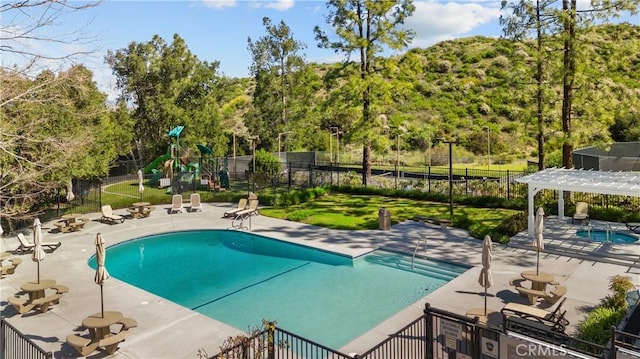 24239 Bella Ct, Newhall, CA 91321 - community pool with a playground, a pergola, a patio, and view of scattered trees