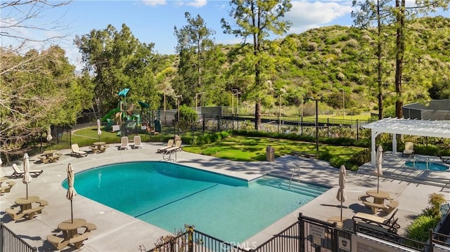24239 Bella Ct, Newhall, CA 91321 - community pool featuring a playground, a pergola, a patio, and view of scattered trees