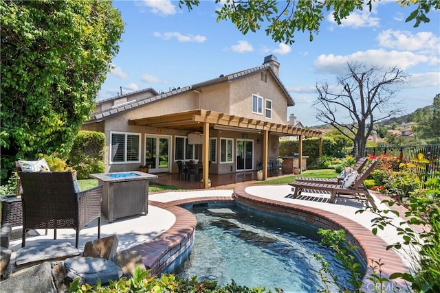 24239 Bella Ct, Newhall, CA 91321 - back of house featuring stucco siding, an outdoor fire pit, fence, a chimney, and a ceiling fan