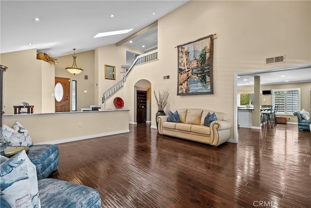 24239 Bella Ct, Newhall, CA 91321 - living room with arched walkways, wood finished floors, high vaulted ceiling, baseboards, and a skylight