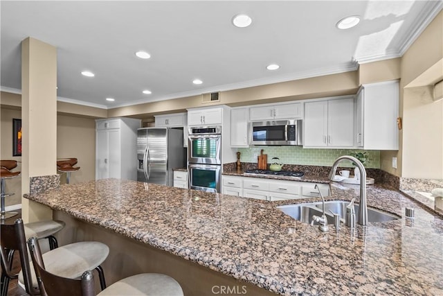 24239 Bella Ct, Newhall, CA 91321 - kitchen featuring stainless steel appliances, a sink, dark stone countertops, a peninsula, and crown molding