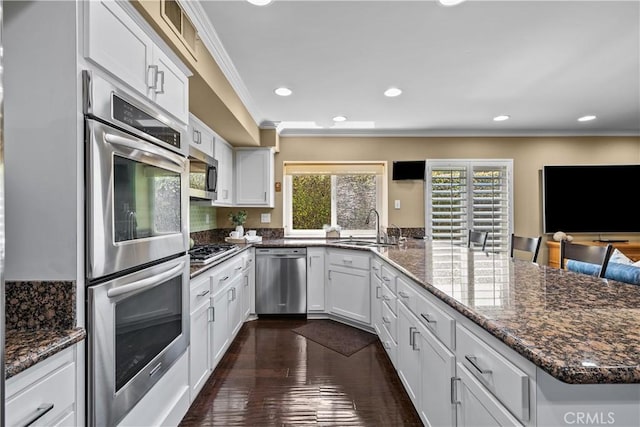 24239 Bella Ct, Newhall, CA 91321 - kitchen with appliances with stainless steel finishes, a sink, a peninsula, crown molding, and white cabinetry