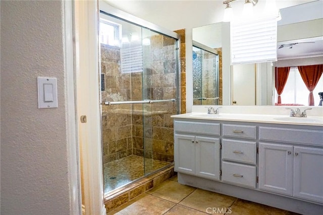bathroom with a sink, tile patterned floors, a textured wall, and a shower stall