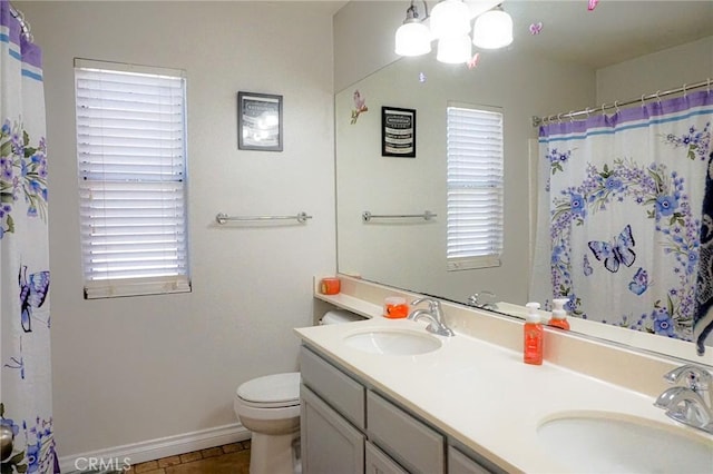 bathroom featuring a sink, baseboards, toilet, and double vanity