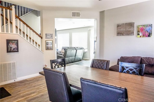 dining room featuring baseboards, visible vents, wood finished floors, and stairway