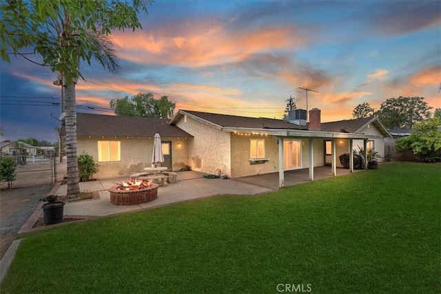 back of house featuring a chimney, a patio area, a yard, a fire pit, and stucco siding