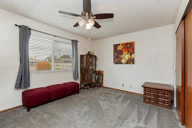 sitting room with baseboards, a ceiling fan, carpet, and a textured ceiling