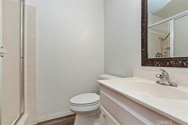 bathroom with vanity, a textured wall, wood finished floors, toilet, and an enclosed shower