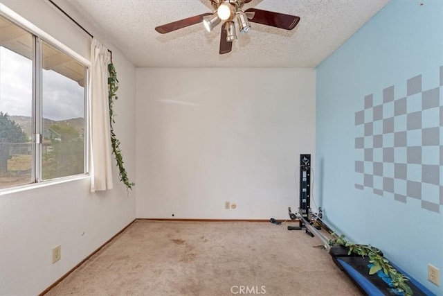 carpeted empty room featuring plenty of natural light, a ceiling fan, and a textured ceiling