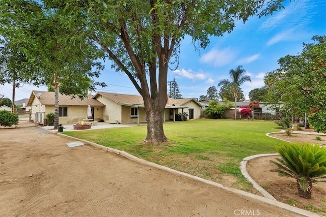 view of front of home with a patio area, an outdoor fire pit, fence, and a front yard