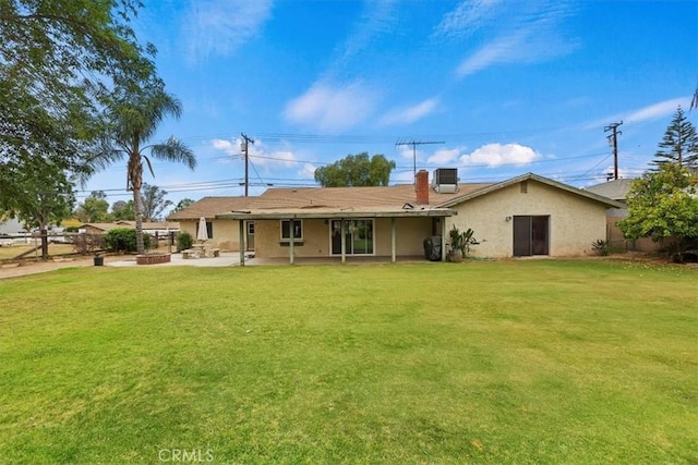 rear view of house featuring a lawn, cooling unit, a patio area, and stucco siding