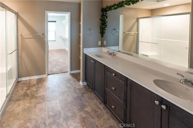 full bath with baseboards, a sink, and a shower with shower door