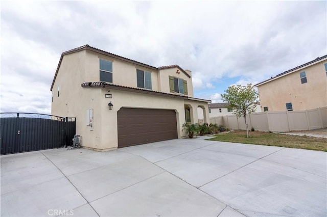 exterior space featuring fence, an attached garage, stucco siding, a gate, and concrete driveway